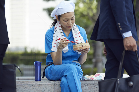 在办公楼下吃午餐的女清洁员图片