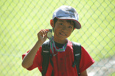 一个穿运动装的棒球男孩手拿奖杯图片