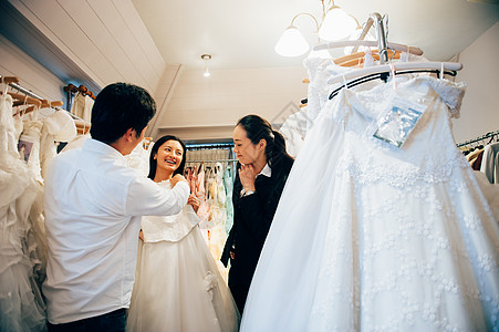 在新郎的陪伴下新娘与婚礼策划师挑选婚纱图片