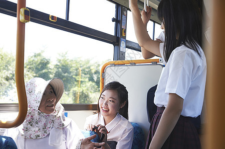  一群小姑娘与坐公交车的奶奶交谈 图片
