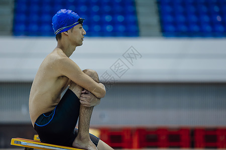 跳水运动员坐在泳池边思考的游泳运动员背景