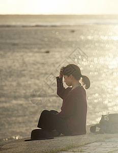 黄昏夕阳下年轻女人坐在海边图片