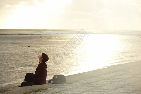 黄昏夕阳下年轻女人坐在海边图片