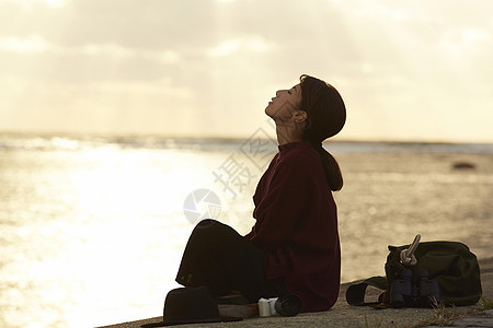 黄昏夕阳下年轻女人坐在海边图片