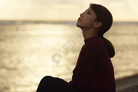 黄昏夕阳下年轻女人坐在海边图片