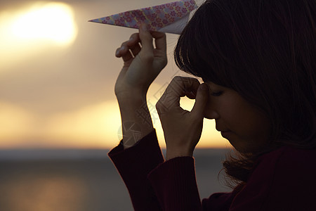 女人在夕阳下手拿纸飞机图片