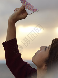 女人在夕阳下手拿纸飞机图片