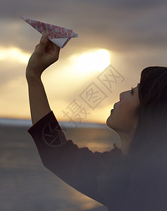 女人在夕阳下手拿纸飞机图片