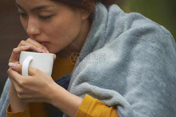 披着毛毯喝咖啡的女性图片