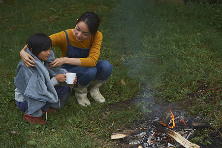 蹲在篝火旁时妈妈给孩子盖上毛毯图片