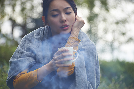 闲散蹲在篝火旁取暖喝咖啡的女人背景