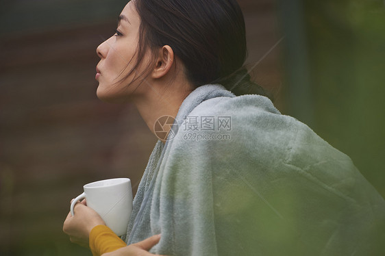 蹲在篝火旁取暖喝咖啡的女人的侧脸图片