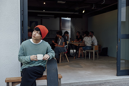 年轻人端着茶杯坐在门口边图片