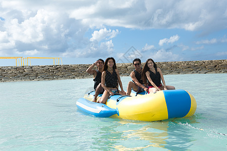 水中的女人享受假期坐在香蕉船的两对情侣背景