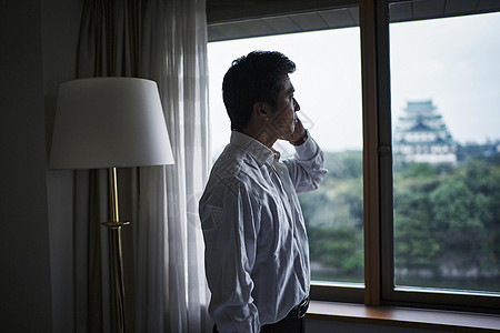 站在旅馆窗口打电话的一个商人图片