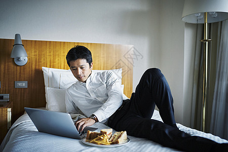 商务男人在床上享用酒店早餐图片