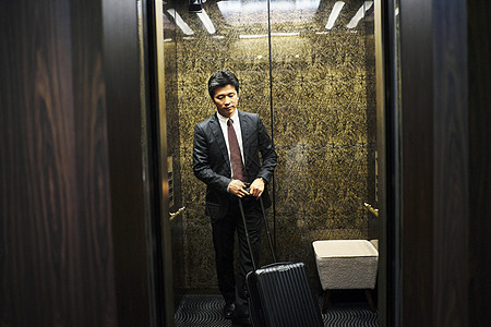 商务男子拎着行李箱入住酒店坐电梯图片