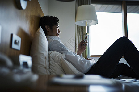 在酒店床上玩手机的男人图片