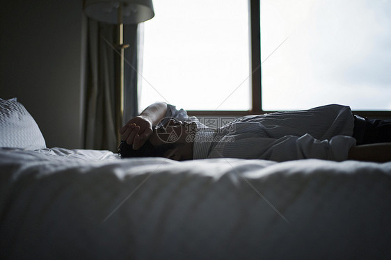 精疲力竭的白领躺在酒店床上图片