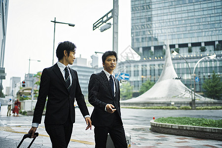 亚洲人手提袋走路在商务旅行驻地前面的商人图片