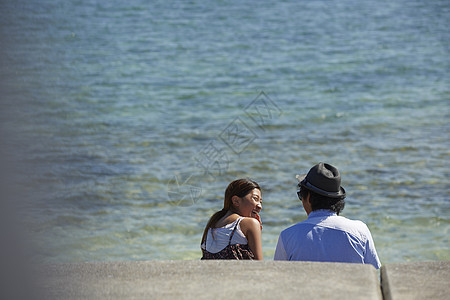  坐在海边看海聊天的情侣图片