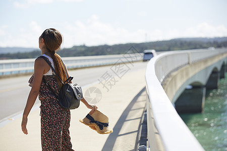 旅途中的女性走在海面大桥上图片