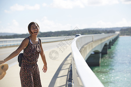 旅途中情侣手牵着手走在海上大桥上图片