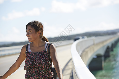 旅途中的女性走在海面大桥上图片