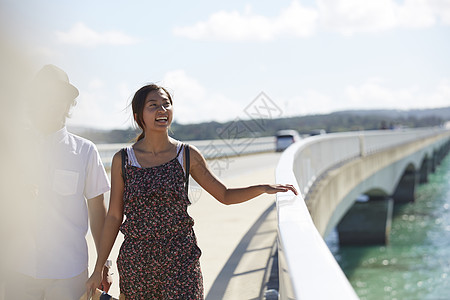 旅途中情侣手牵着手走在海上大桥上图片