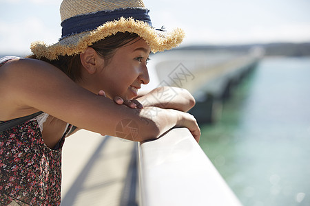 旅途中的女性走在海面大桥上看风景图片