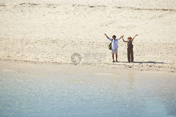 在浅蓝色海岸边牵手看风景的情侣图片