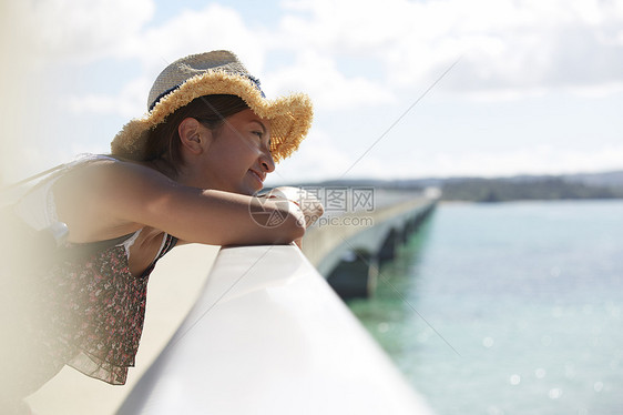 女人在桥上放松微笑看大海图片
