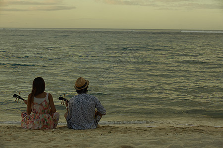  坐在沙滩上的弹吉他一对情侣图片