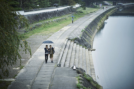 撑伞走在河堤边的年轻情侣图片