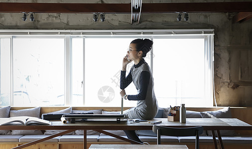   坐在办公桌上打电话的女性图片