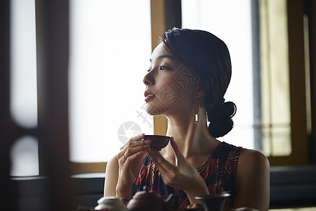 女游客端着茶杯看窗外图片