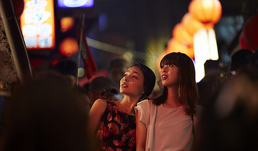 在夜市和朋友一起逛街的女游客图片