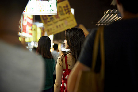 在夜市逛街的女游客背影图片