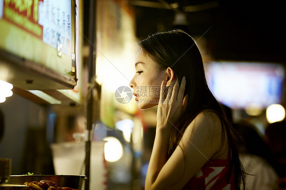 在夜市逛街的女游客摸头发图片