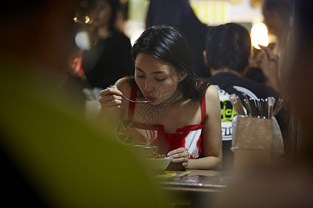 在夜市逛街的女游客吃小吃图片素材
