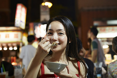 在夜市逛街的女游客吃小吃图片素材