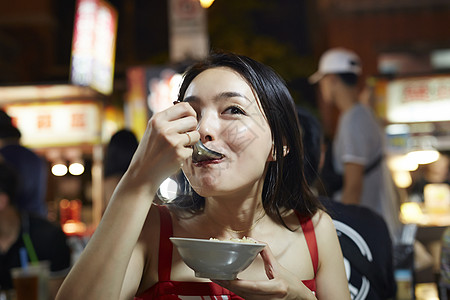 在夜市逛街的女游客吃小吃图片素材