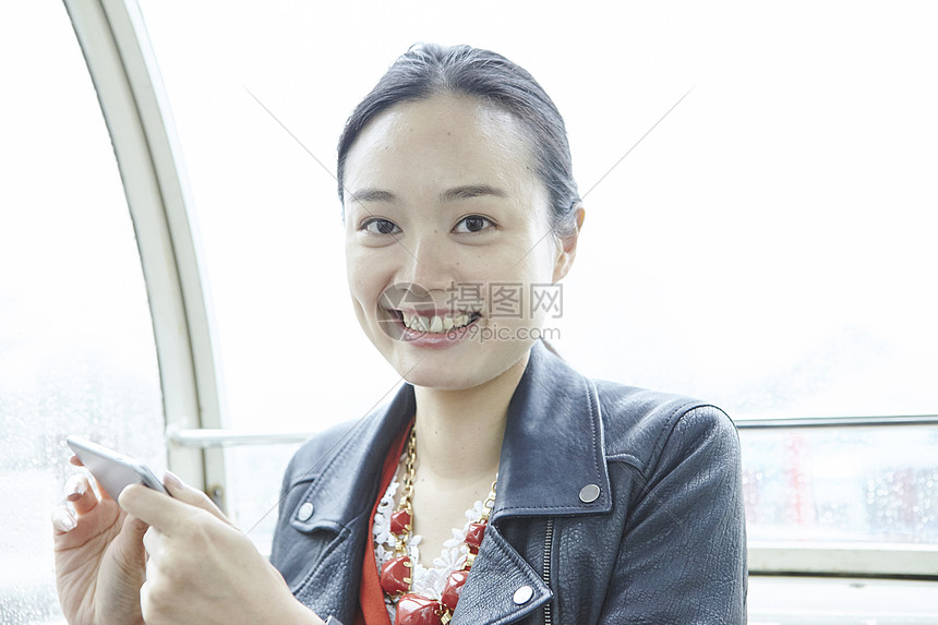 在游乐园摩天轮上的女人拿着手机看镜头图片