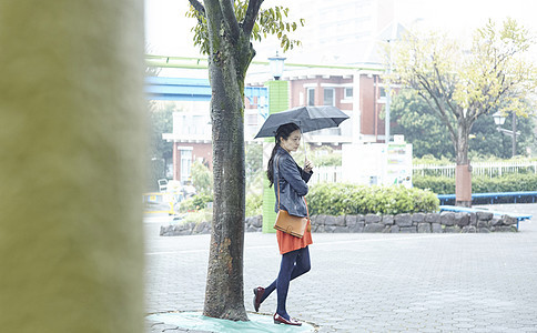 打着伞的女人在游乐园树下站着图片