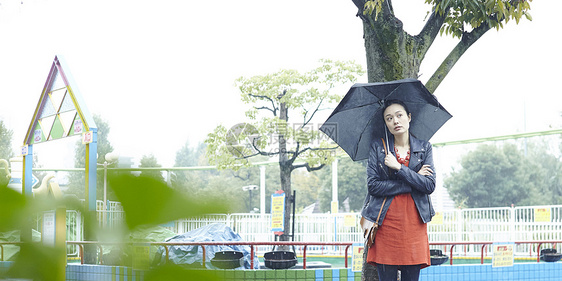 打着伞的女人在游乐园树下站着图片