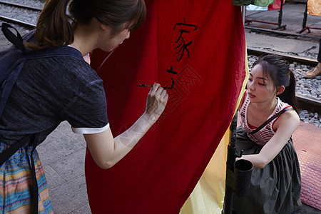 两个女游客在祈福灯笼上写字图片