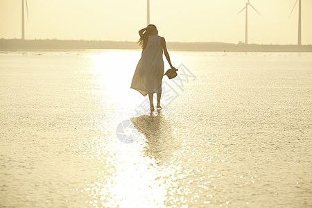 日落时分走在海滩边上长裙美女图片
