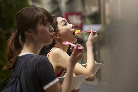 旅游的姐妹在路边吃水果冷饮图片