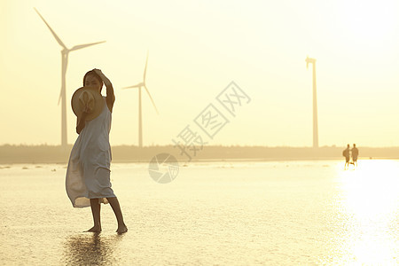 日落时分走在海滩边上长裙美女图片