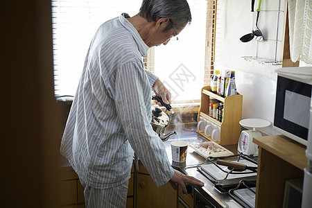 独居的老人在厨房给速食产品倒水图片